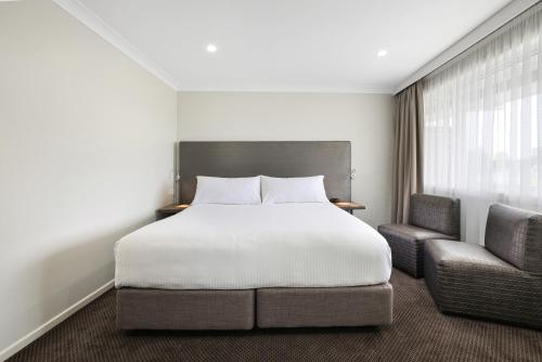 a bedroom with a bed and two chairs at The Duck Inn Apartments in Tamworth