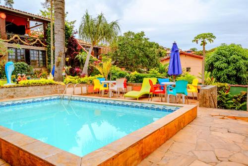 een zwembad met stoelen en een tafel en parasol bij Suítes Casa do Barão in Búzios