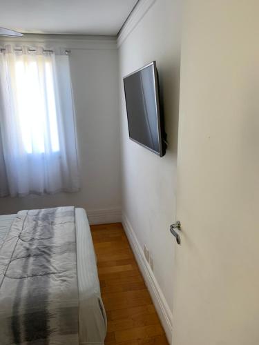 a bedroom with a flat screen tv on the wall at Quartos Vila Augusta/Guarulhos in Guarulhos