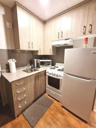 a kitchen with a white refrigerator and wooden cabinets at Cozy Sweet Studio #1, 10 minutes to D.T. Ottawa in Gatineau