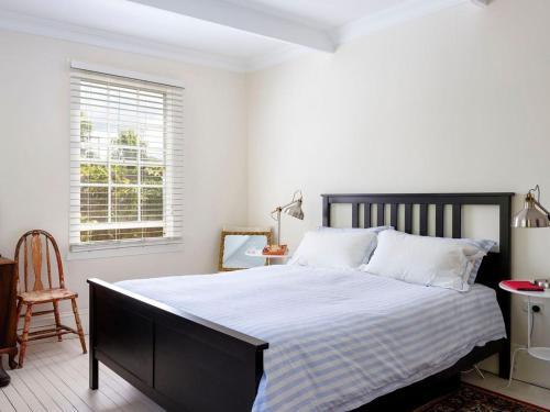 a bedroom with a large bed with white sheets and a window at Witts Oasis Two traditional Tea Gardens cottages in Tea Gardens