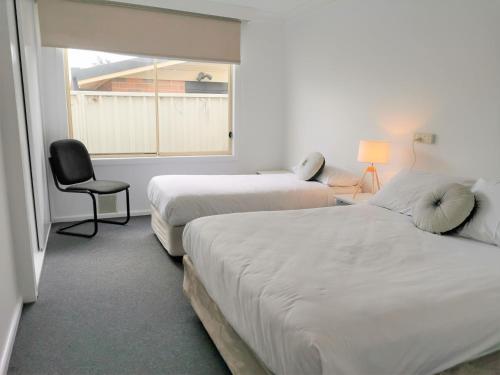 Zimmer mit 2 Betten, einem Stuhl und einem Fenster in der Unterkunft Bathurst Explorers Motel in Bathurst