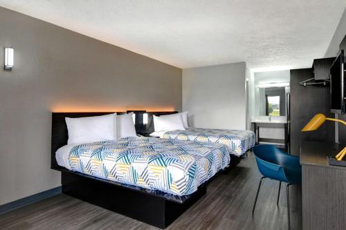 a hotel room with two beds and a blue chair at Studio 6 Meridian, MS Bonita Lakes in Meridian