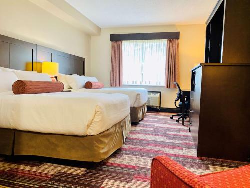 a hotel room with two beds and a television at Best Western Plus Stoneridge Inn & Conference Centre London Ontario in London