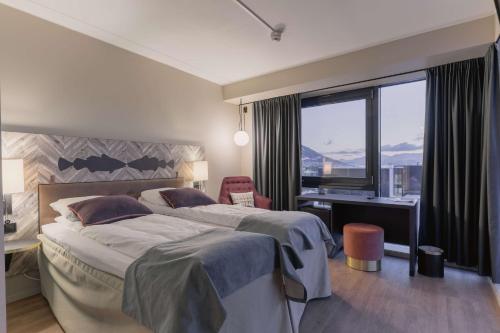 a bedroom with two beds and a desk and a window at Scandic Grand Tromsø in Tromsø