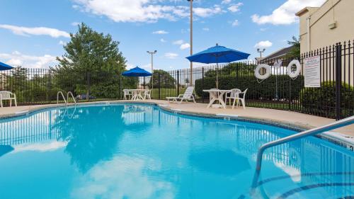 a swimming pool with tables and chairs and umbrellas at Best Western Historic Frederick in Frederick