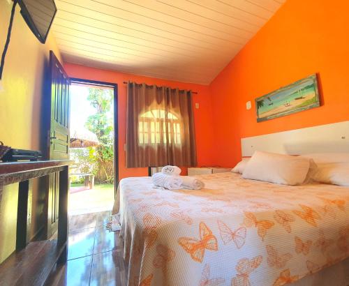 een slaapkamer met een bed met een oranje muur bij Suítes Casa do Barão in Búzios