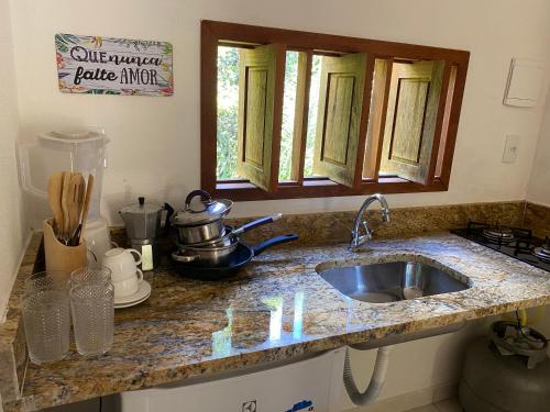 Loft Reserva Sapiranga Praia do Forte Vila Hen 102 في ماتا دي ساو جواو: طاولة مطبخ مع حوض في المطبخ