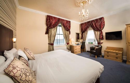 a hotel room with a bed and a chair and windows at BEST WESTERN New Holmwood Hotel in Cowes