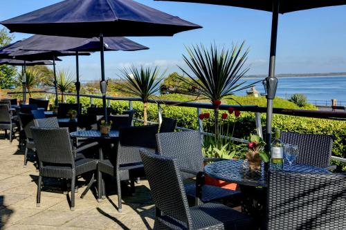 a patio with tables and chairs and umbrellas at BEST WESTERN New Holmwood Hotel in Cowes