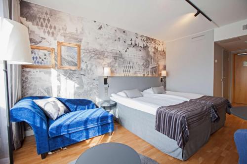 a bedroom with a large bed and a blue chair at Scandic Kuopio in Kuopio