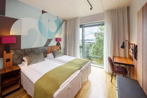 a bedroom with a bed and a desk and a window at Scandic Solli in Oslo