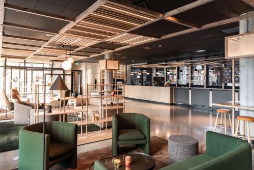 a lobby with green chairs and tables and shelves at Scandic Hamar in Hamar