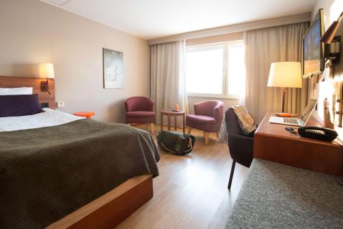 a hotel room with a bed and a desk with a laptop at Scandic Bollnäs in Bollnäs