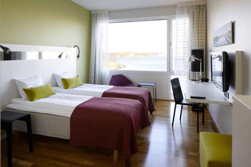 a hotel room with two beds and a desk and a window at Scandic Karlskrona in Karlskrona
