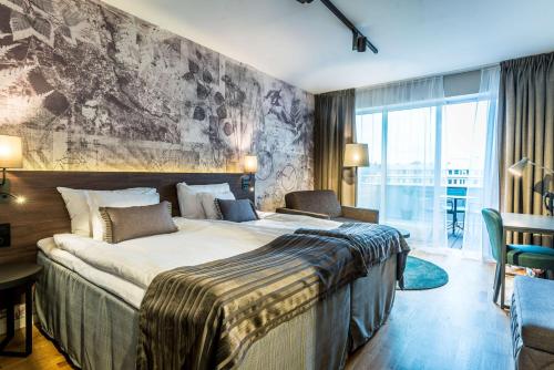 a hotel room with a large bed and a large window at Scandic Frimurarehotellet in Linköping