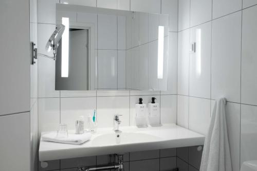 ein weißes Badezimmer mit einem Waschbecken und einem Spiegel in der Unterkunft Scandic Winn in Karlstad