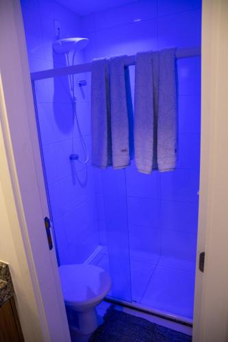 a bathroom with a shower and a toilet in a blue light at Flat em Guarajuba in Guarajuba