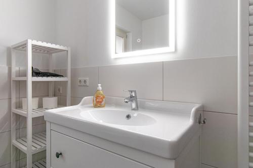 a white bathroom with a sink and a mirror at Ferienwohnungen Galerie im Klink in Quedlinburg