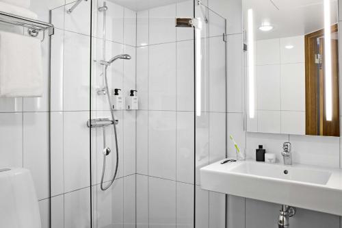 a bathroom with a shower, sink, and mirror at Scandic Norra Bantorget in Stockholm