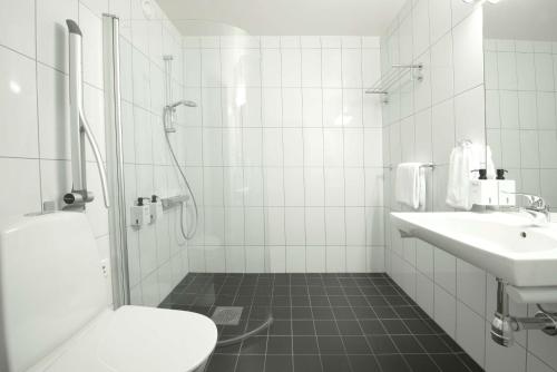 a white bathroom with a toilet and a sink at Scandic Sundsvall Nord in Sundsvall