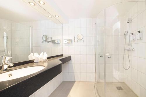 a bathroom with a shower, sink, and tub at Scandic Victoria in Oslo