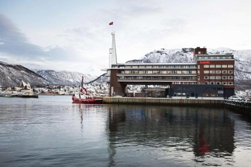 a building with a red boat in the water at Scandic Ishavshotel in Tromsø