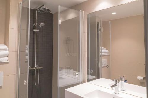a bathroom with a shower and a sink and a mirror at Scandic Ishavshotel in Tromsø