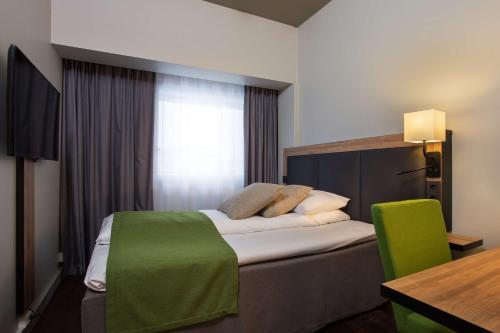 a hotel room with a bed with a green blanket at Scandic Sarpsborg in Sarpsborg