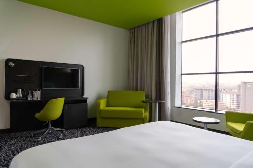 a hotel room with a bed and two chairs and a television at Park Inn by Radisson, Nairobi Westlands in Nairobi
