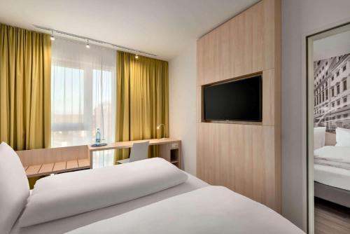 a hotel room with a bed and a television at Super 8 by Wyndham Augsburg in Augsburg