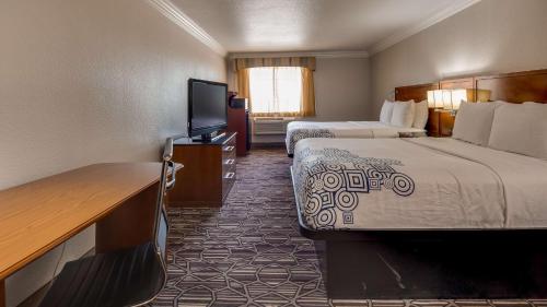 a hotel room with two beds and a flat screen tv at SureStay Plus by Best Western Benbrook Fort Worth in Fort Worth