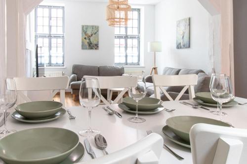 ein Esszimmer mit einem Tisch mit grünen Tellern und Weingläsern in der Unterkunft Ferienwohnungen BUNTER HOF Quedlinburg in Quedlinburg