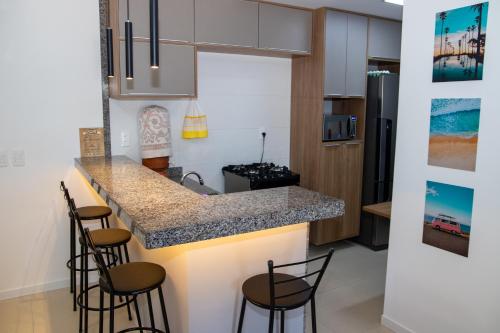 eine Küche mit einer Theke mit Hockern drum herum in der Unterkunft Flat em Guarajuba in Guarajuba