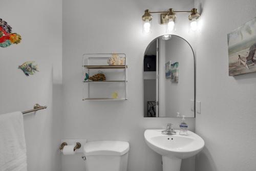 La salle de bains est pourvue d'un lavabo, de toilettes et d'un miroir. dans l'établissement Emerald Coast Cabana, à Panama City Beach
