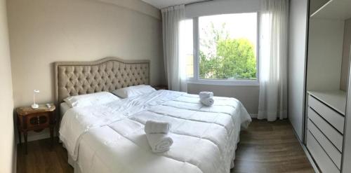 um quarto com uma grande cama branca e uma janela em Exclusivo Departamento Céntrico em San Carlos de Bariloche