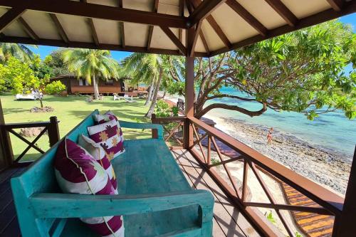 a blue bench sitting on a porch next to the beach at Villa Ylang Ylang in Haapiti