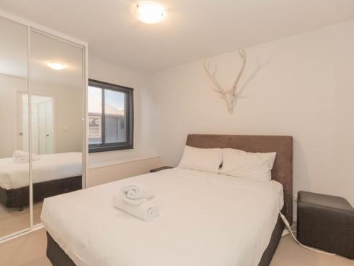 a bedroom with a large bed and a mirror at Edge 6 16 Clyde Street in Jindabyne