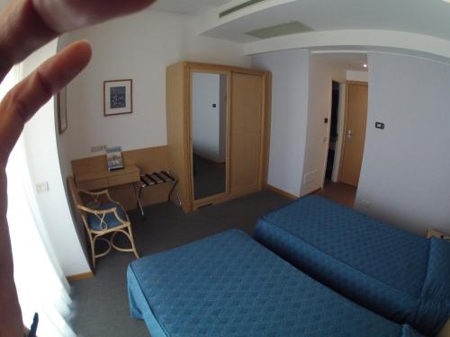 a room with two blue beds and a desk at City Hotel in Senigallia