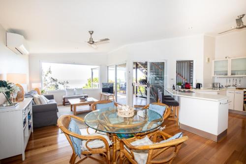 cocina y sala de estar con mesa de cristal y sillas en BEST OCEAN VIEWS ON STRADDIE + SUNSET DECK en Point Lookout