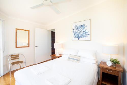 1 dormitorio blanco con 1 cama y 1 silla en BEST OCEAN VIEWS ON STRADDIE + SUNSET DECK en Point Lookout