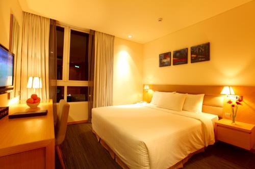 a hotel room with a white bed and a desk at Liberty Central Saigon Centre Hotel in Ho Chi Minh City