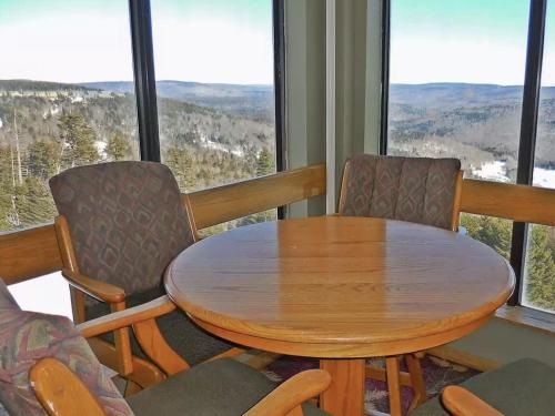 a wooden table and chairs in a room with windows at Enjoy the Long Range View, Ski in n out Top of the Mountain condo in Snowshoe
