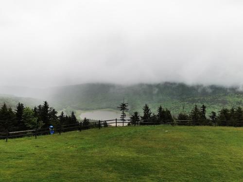 a field with a fence and a lake in the mountains at Enjoy the Long Range View, Ski in n out Top of the Mountain condo in Snowshoe