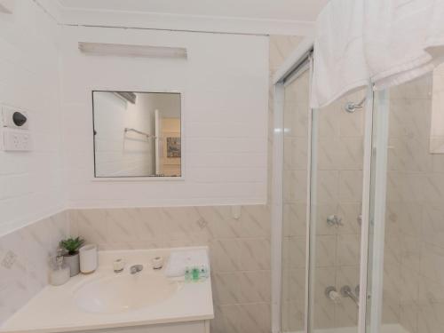 La salle de bains blanche est pourvue d'un lavabo et d'une douche. dans l'établissement Oberlaken 2 125 Gippsland Street, à Jindabyne