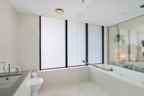 a bathroom with a tub and a toilet and windows at Circle on Cavill 2, 3, 4 & 5 Bedroom SkyHomes & SUB PENTHOUSES by Gold Coast Holidays in Gold Coast