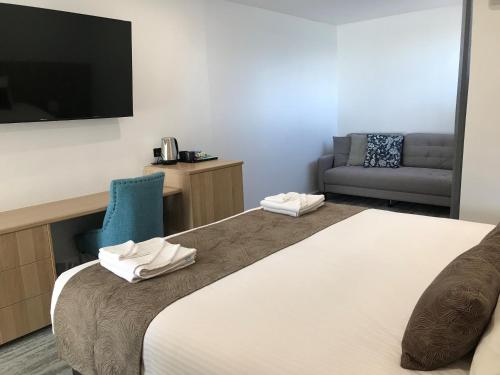 a hotel room with a large bed with a flat screen tv at The Osmond Motel & Apartments in Adelaide