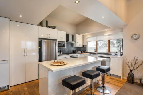 a kitchen with white cabinets and a large island with stools at Alinga in Dinner Plain