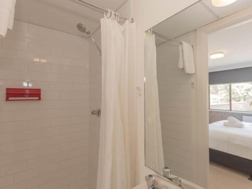 a bathroom with a shower with a shower curtain at Tanderra 17 28 Park Road in Jindabyne