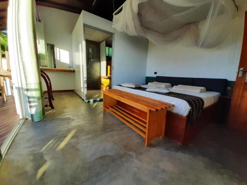 1 dormitorio con cama y banco de madera en Minthu Homestay en Ella